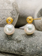 Diamond, gold and pearl earstuds on a stone background