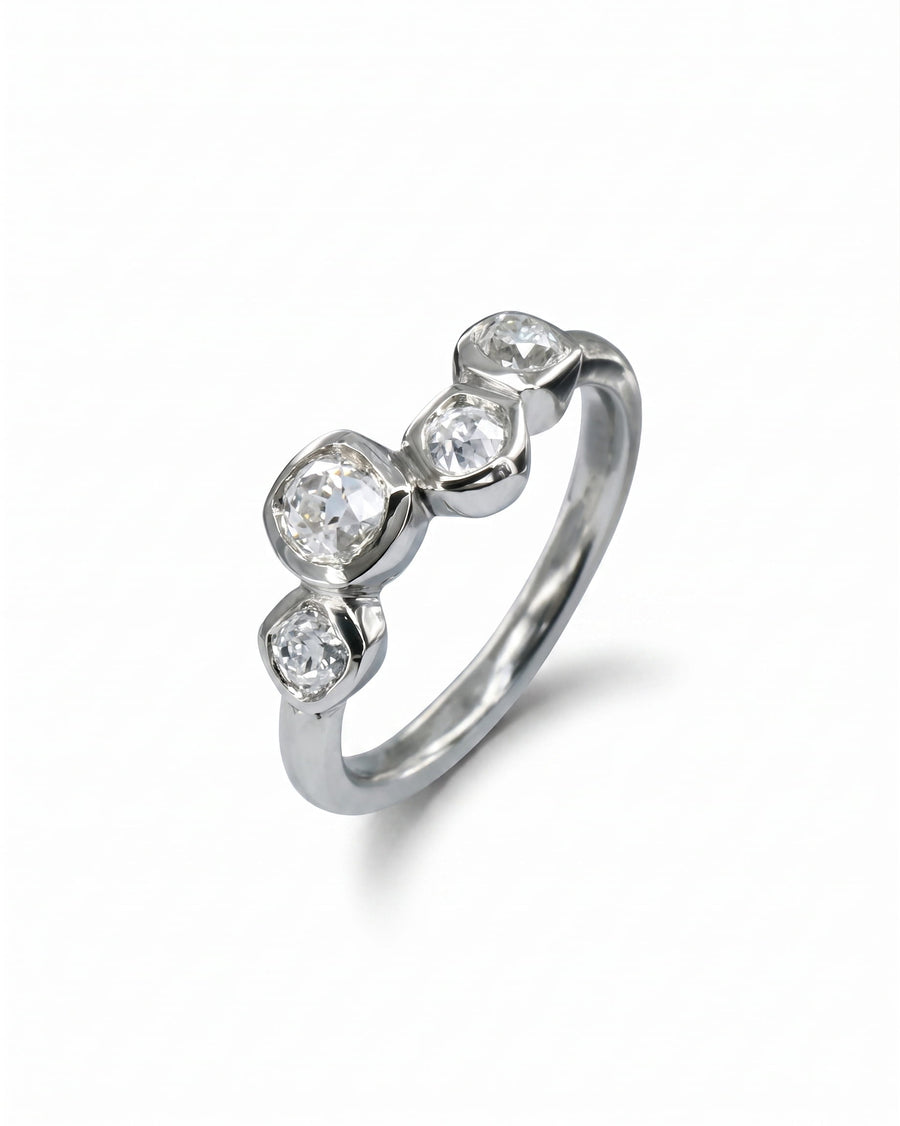 Platinum engagement ring with four offset old cut diamonds.