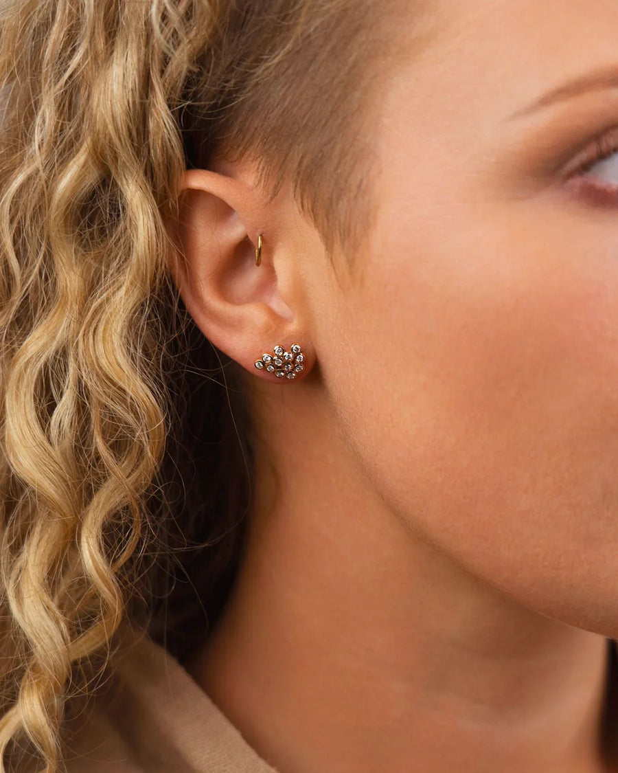 Gold old cut diamond cluster stud earring on an ear.