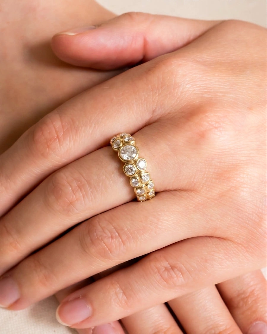 Gold eternity ring with old cut diamonds in varying sizes.