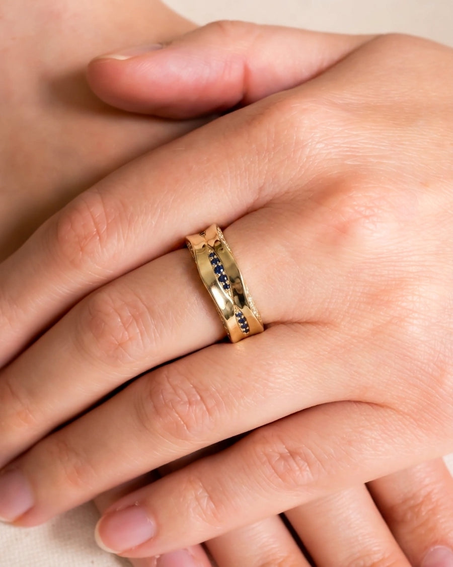 Gold eternity ring with wavy design, set with diamonds and blue sapphires.