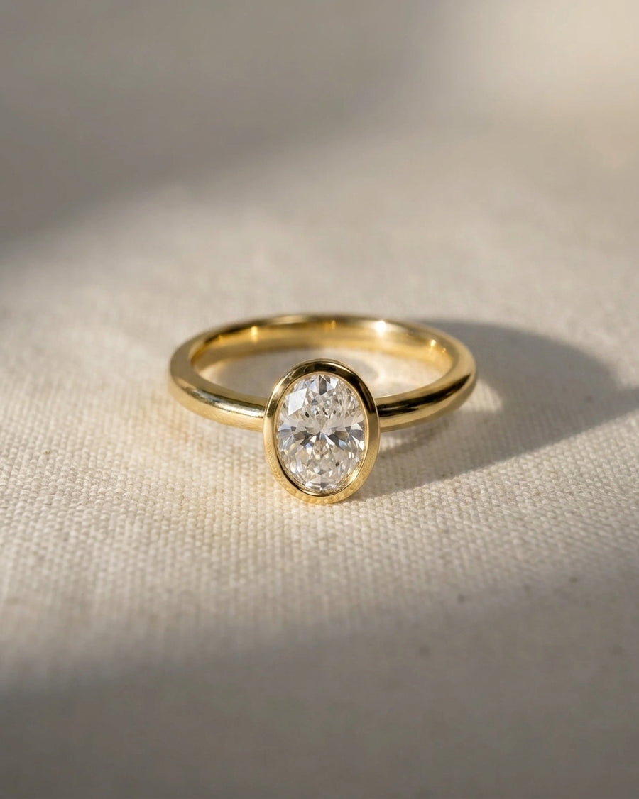 18ct yellow gold engagement ring with a 1ct oval cut lab-grown diamond in a bezel setting.