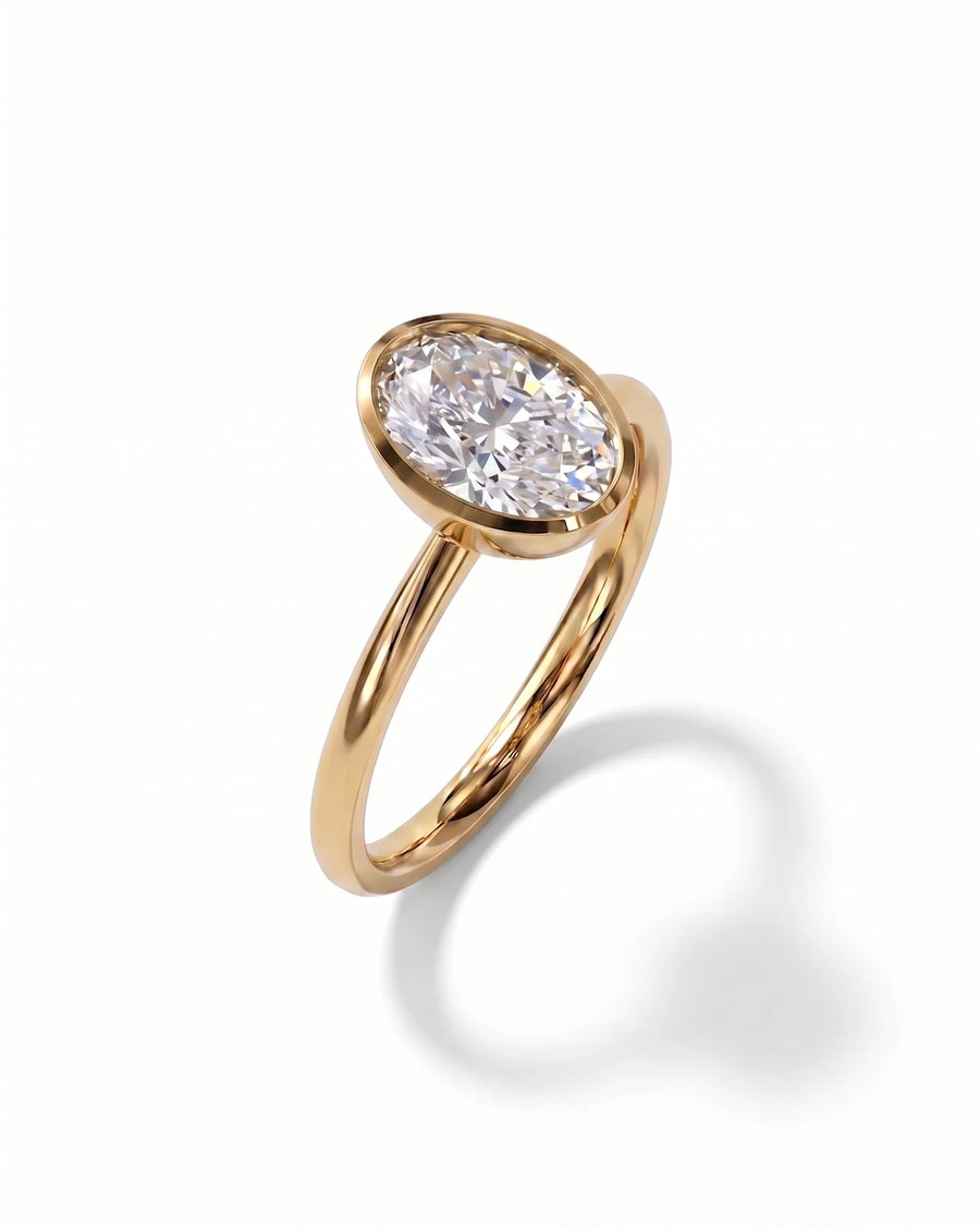 Gold ring with an oval cut diamond in a bezel setting.