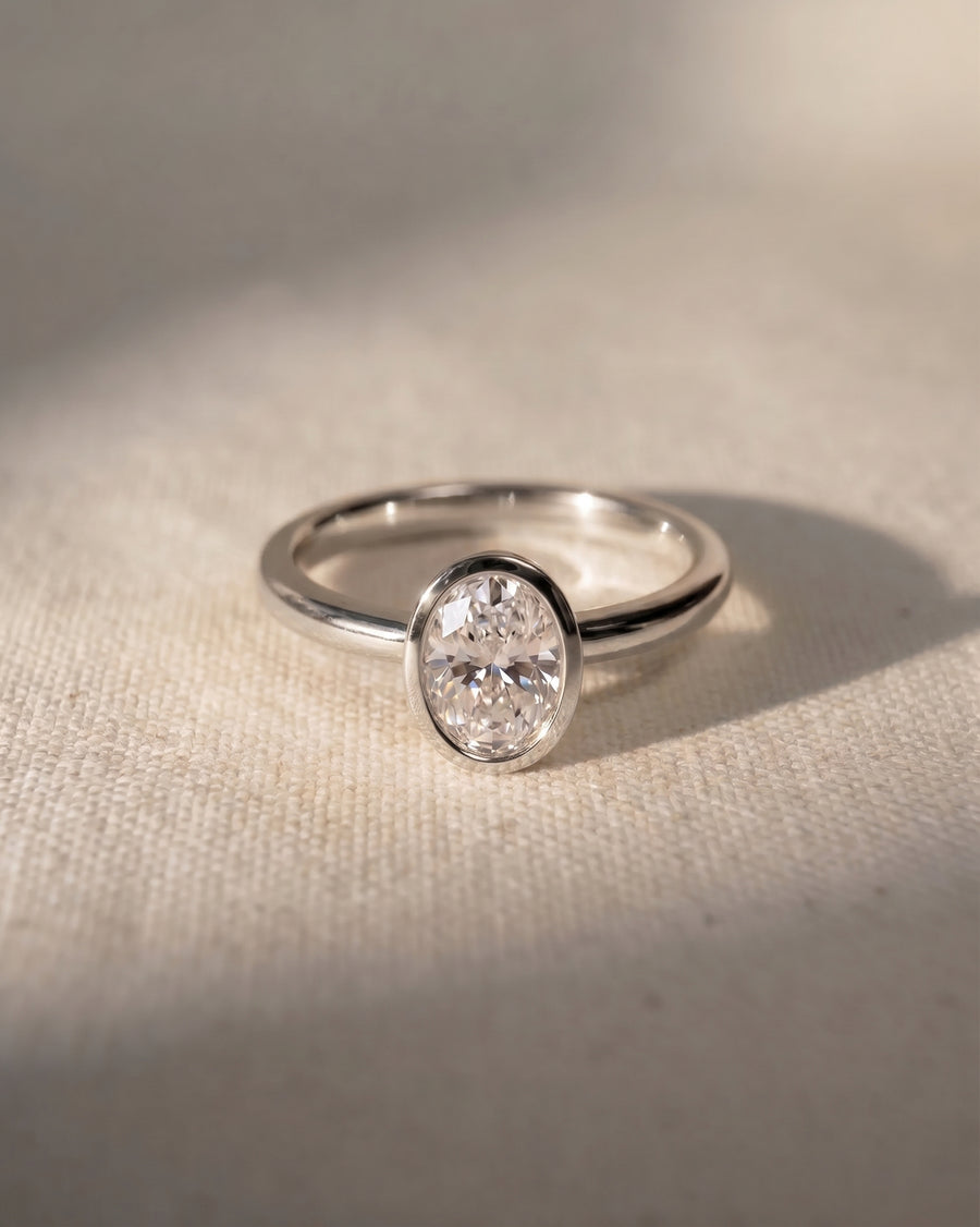 Platinum engagement ring with a 1ct oval lab-grown diamond in a bezel setting.