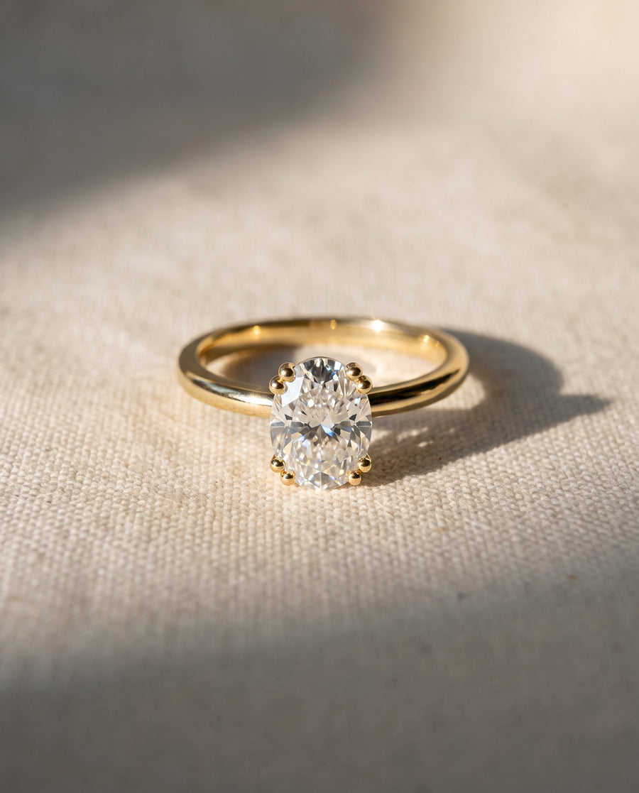 Oval cut diamond engagement ring with a hidden halo on a polished yellow gold band.