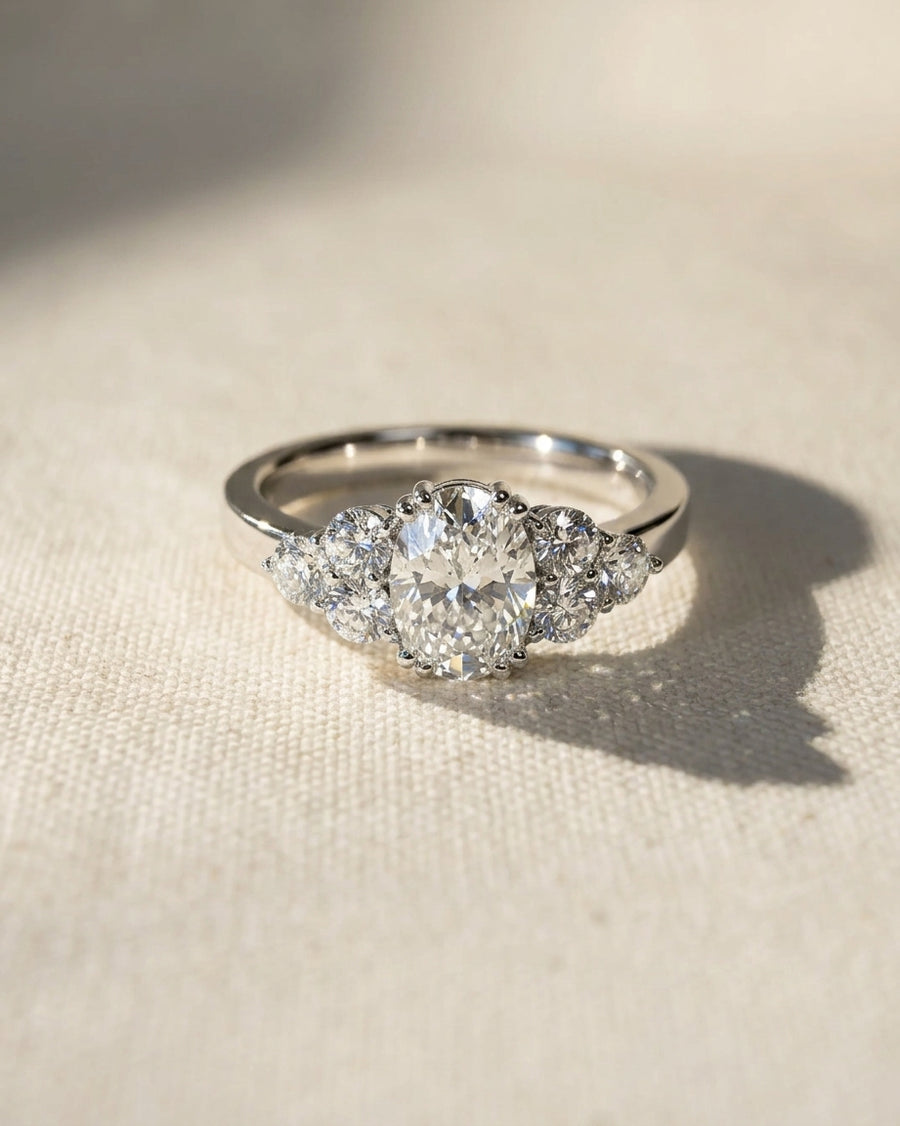 Platinum engagement ring with an oval cut center diamond and four round side diamonds.