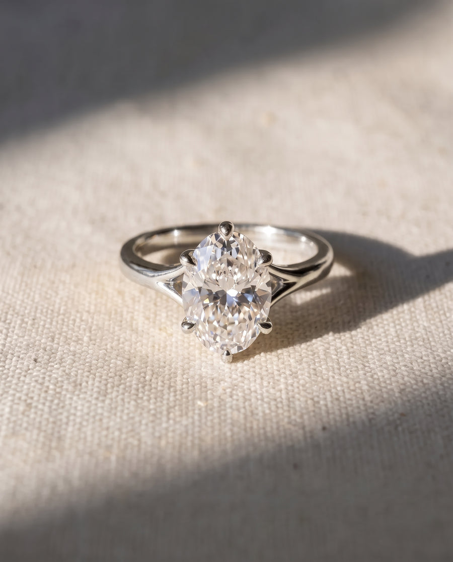 Oval cut diamond engagement ring in a silver-toned metal setting with a tulip claw design.