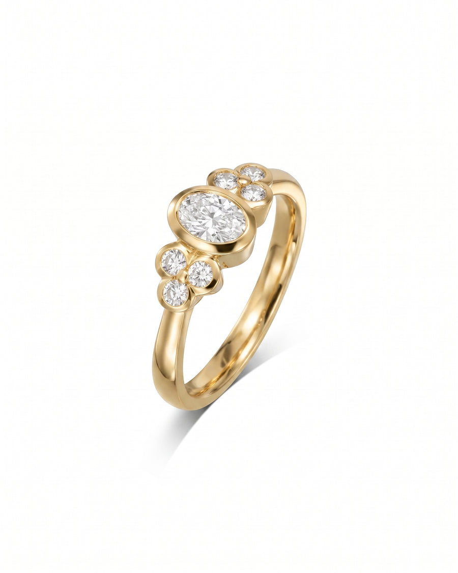 Gold oval trefoil engagement ring with a central oval diamond and surrounding round diamonds.
