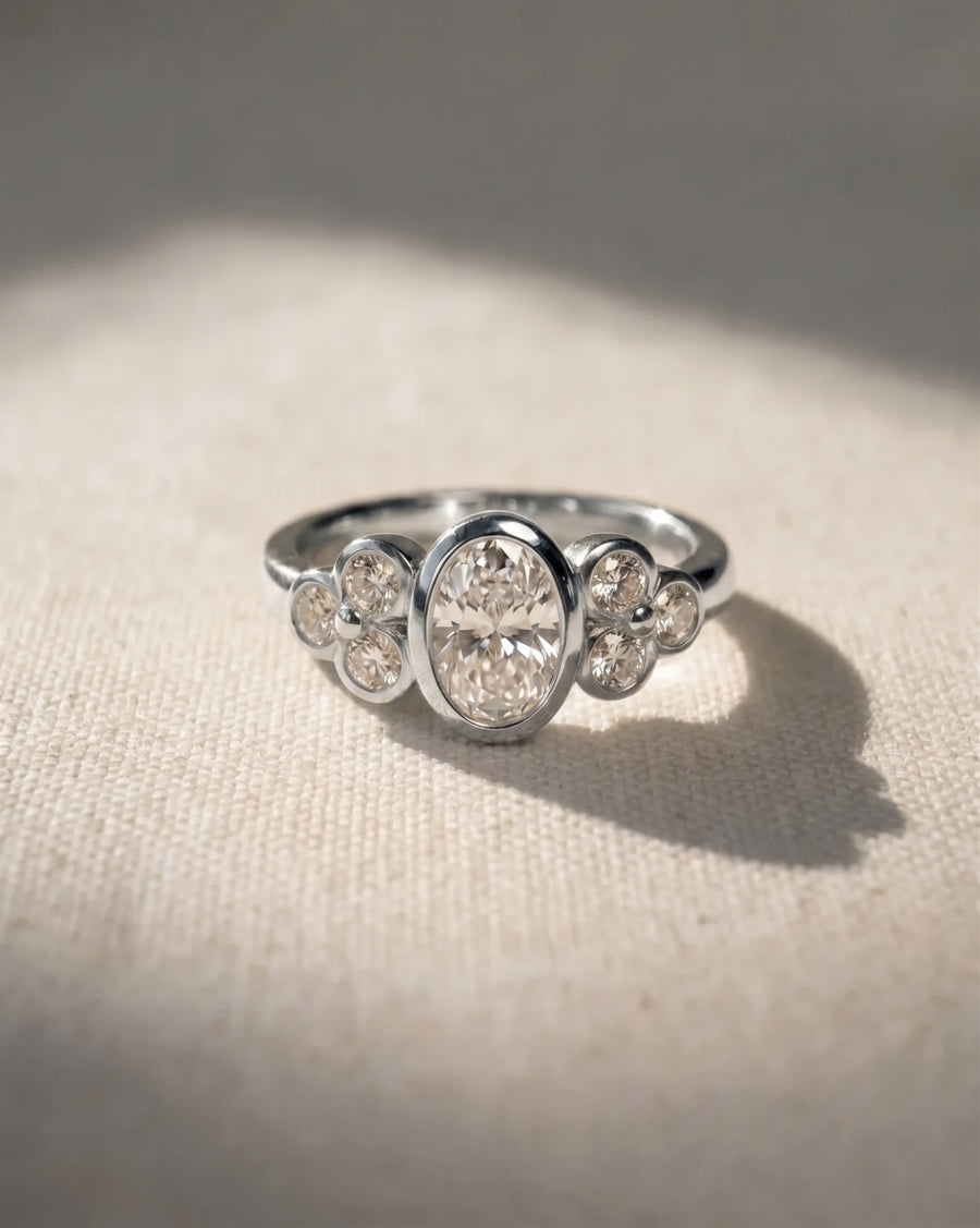 Platinum oval trefoil engagement ring with a center diamond and side diamonds.