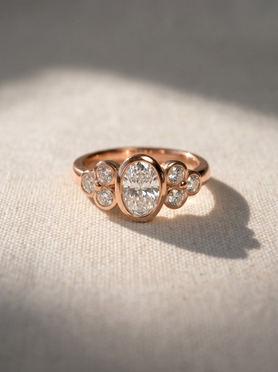 Rose gold oval trefoil engagement ring featuring a central oval diamond flanked by smaller round accent stones.