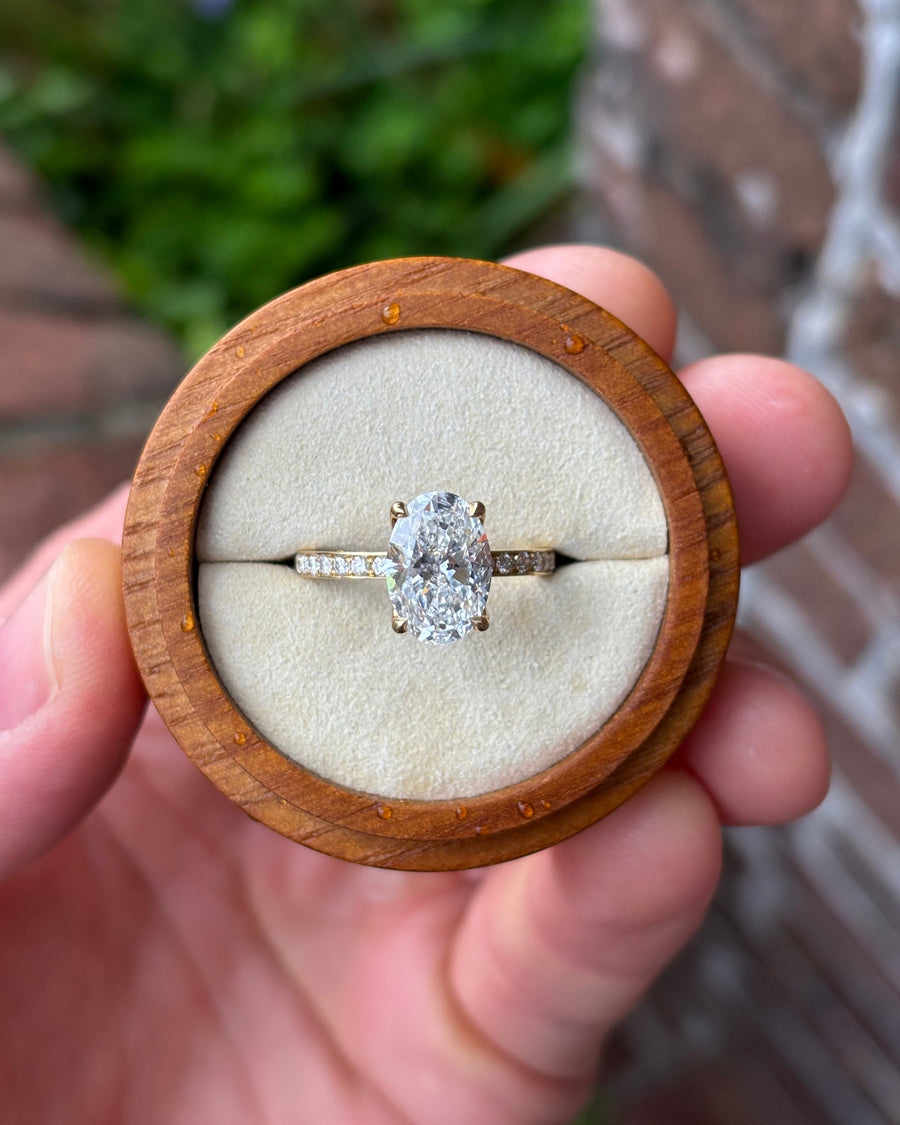 Oval lab-grown diamond solitaire engagement ring with a pavé band set in 18ct yellow gold.