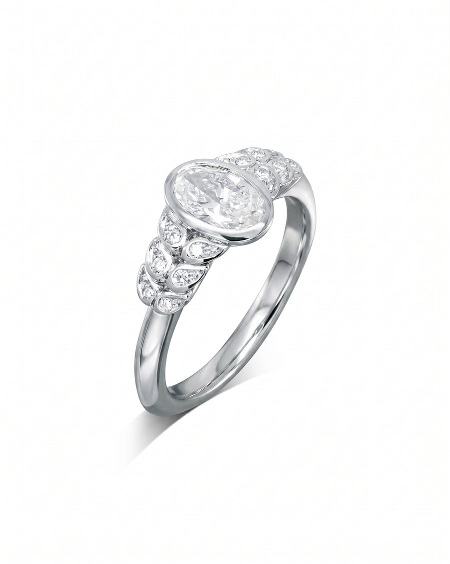White gold engagement ring with an oval diamond and paisley-shaped side diamonds.