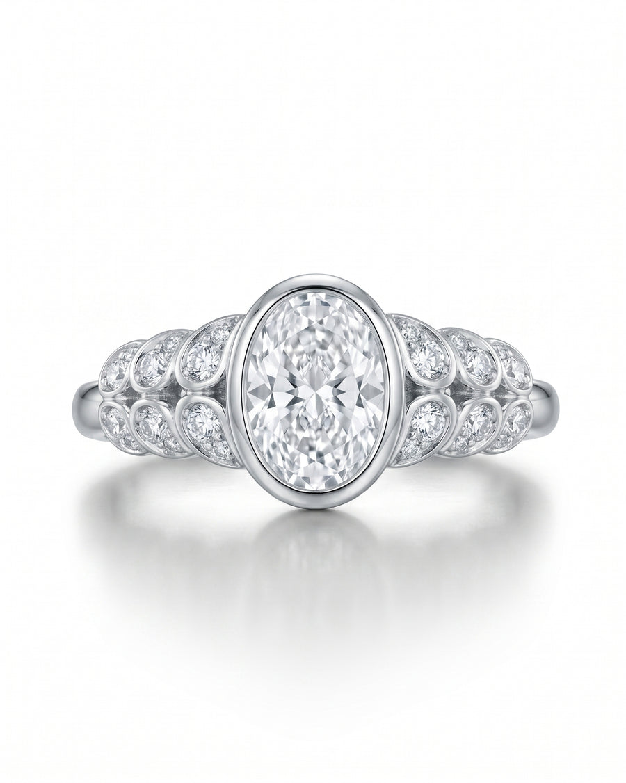 White gold engagement ring with a bezel-set oval diamond and paisley-shaped side diamonds.