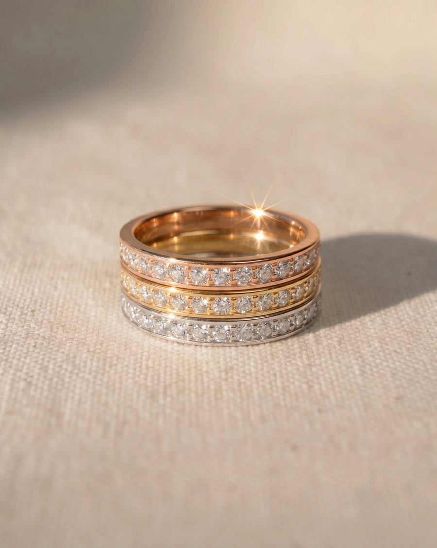 Three pavé diamond rings in rose gold, yellow gold, and white gold.
