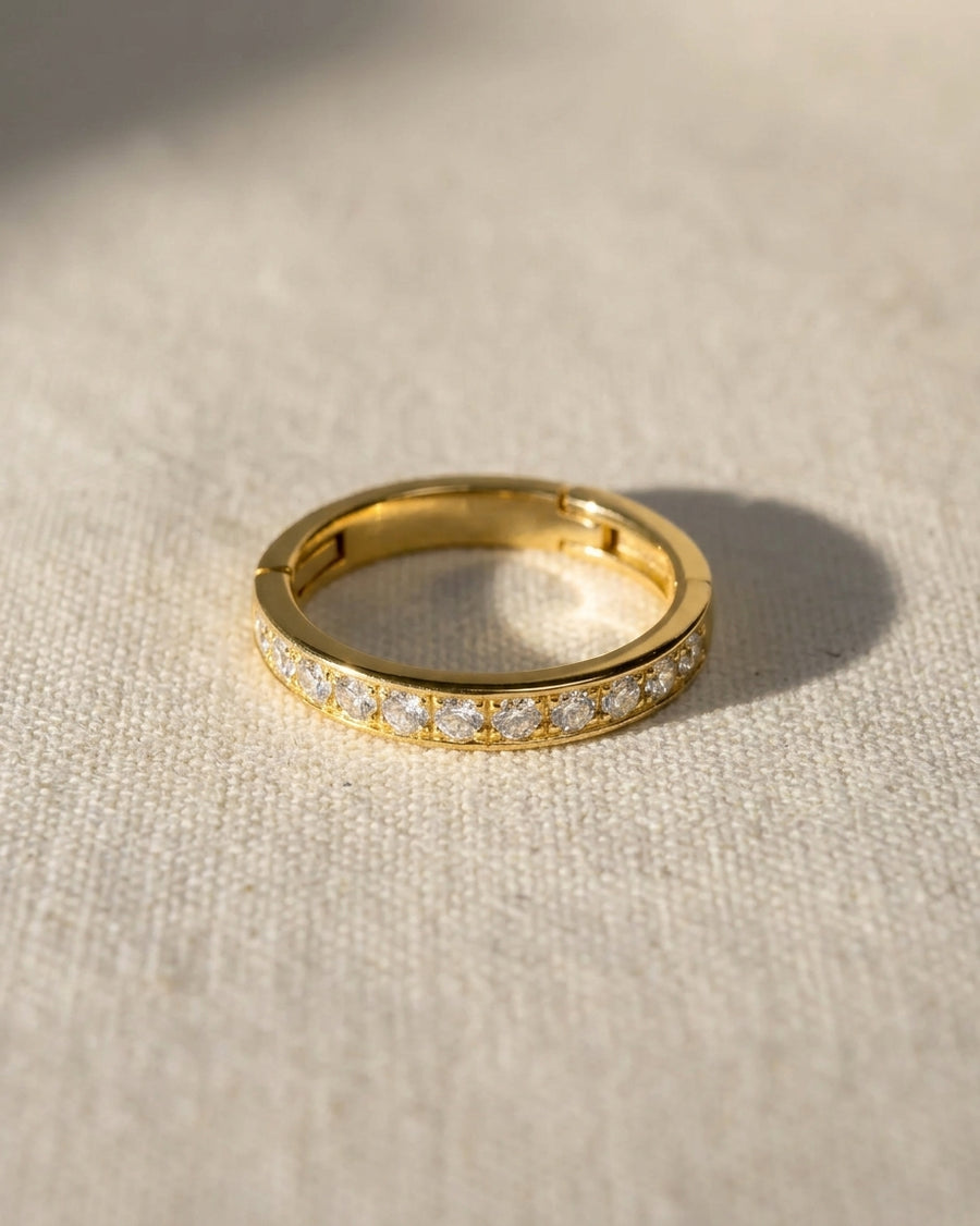 Gold pavé hinged ring with a row of clear gemstones.