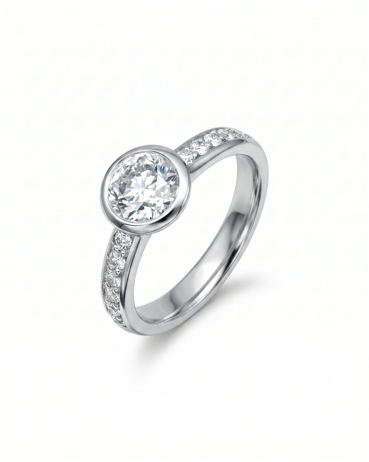 Platinum engagement ring with a round brilliant diamond in a rub-over setting and pavé-set diamond shoulders.