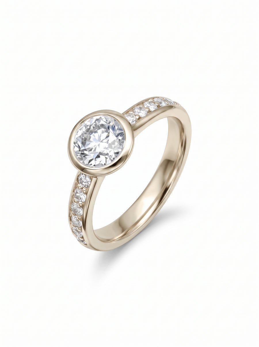 Round diamond engagement ring in yellow gold with a rub-over setting and pavé-set diamond band.