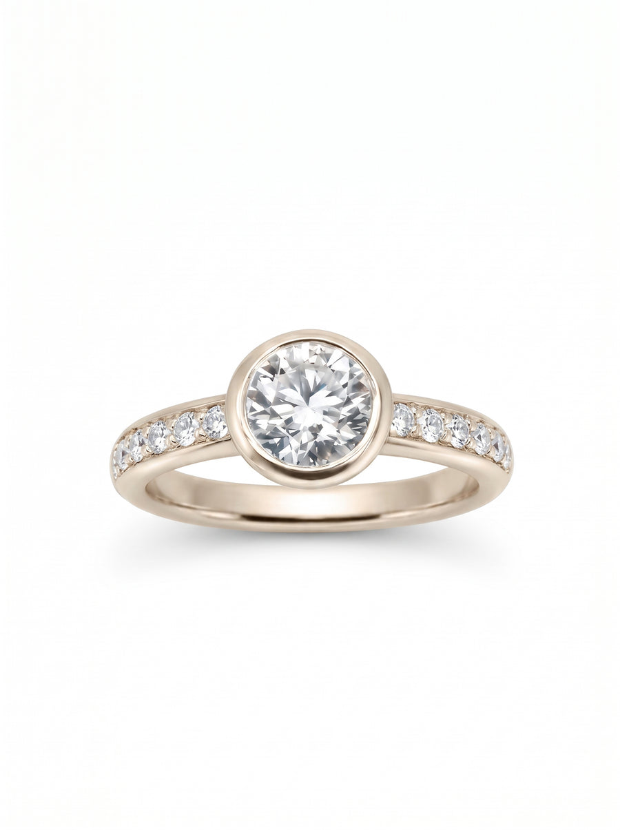 Rose gold engagement ring with a round bezel-set center diamond and pavé-set diamonds along the band.