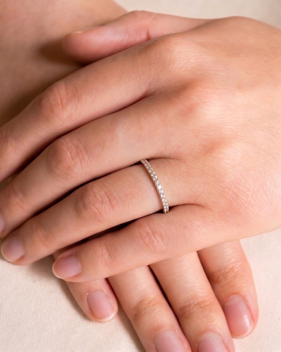 Slim pavé set diamond ring on a hand.