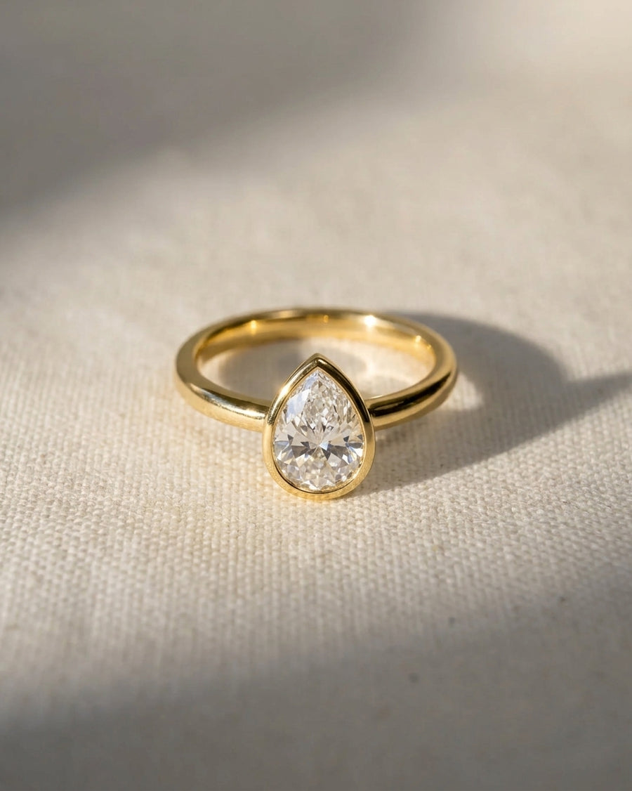 18ct yellow gold engagement ring with a pear cut natural diamond in a bezel setting.