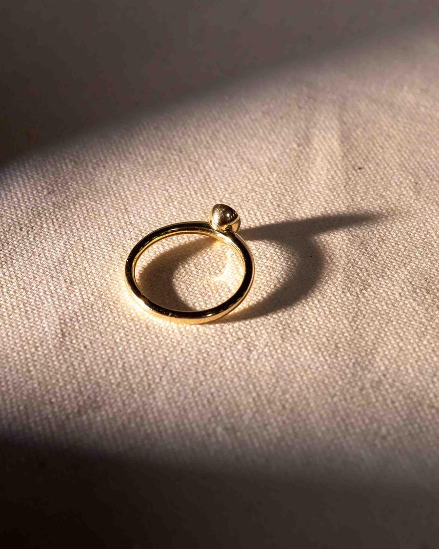 Gold ring with a pear cut natural diamond in a bezel setting.