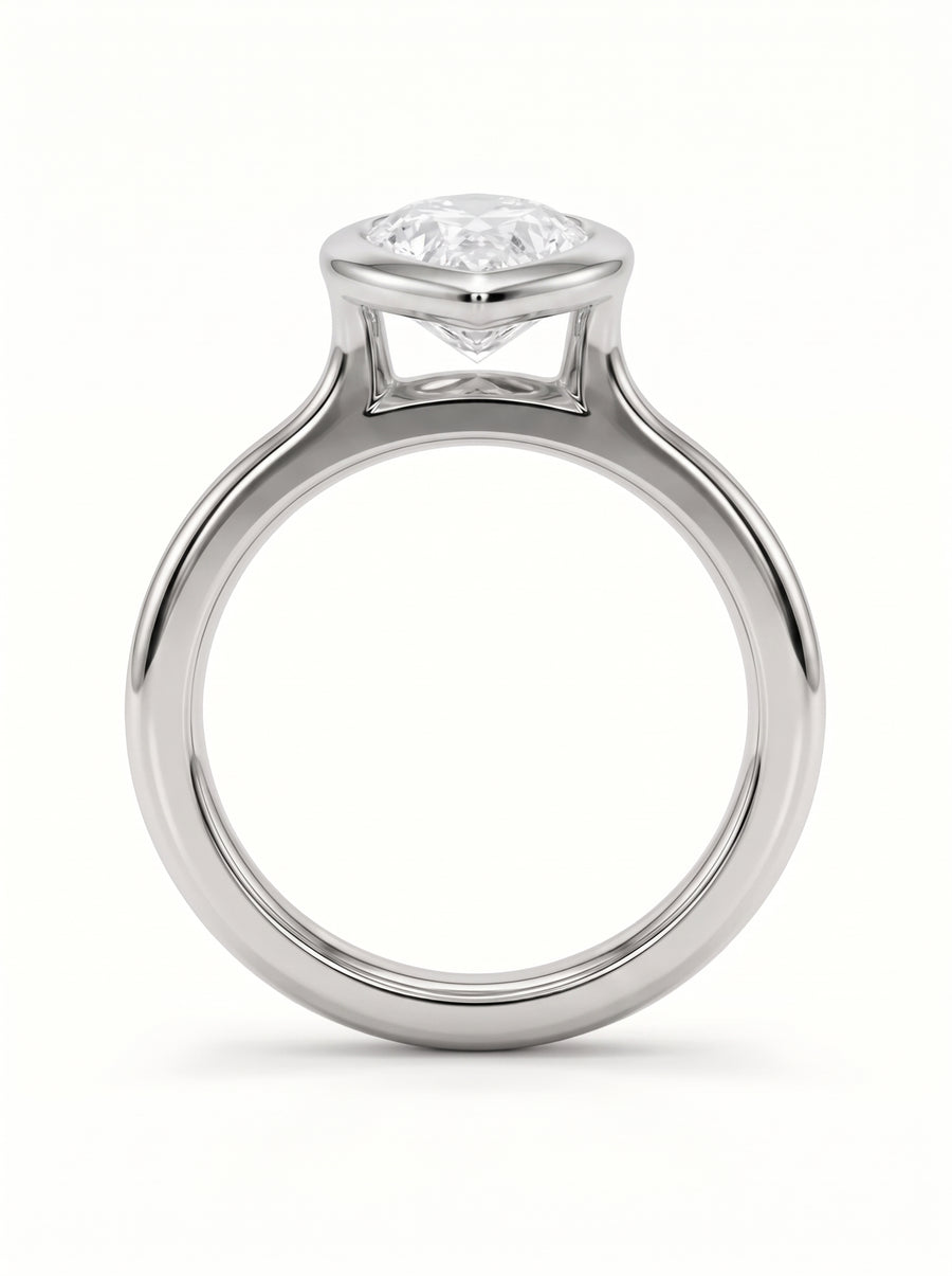 Pear cut diamond engagement ring in a silver-toned metal bezel setting on a white background.