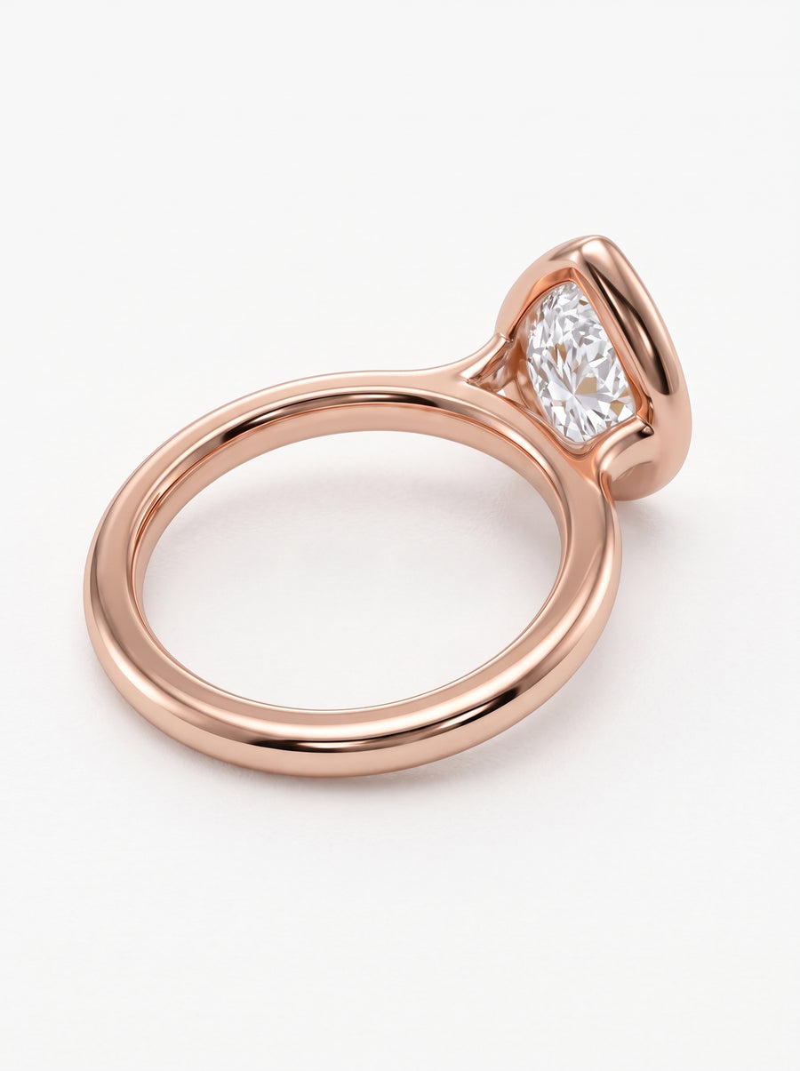 Pear cut diamond engagement ring in a rose gold bezel setting on a white background.