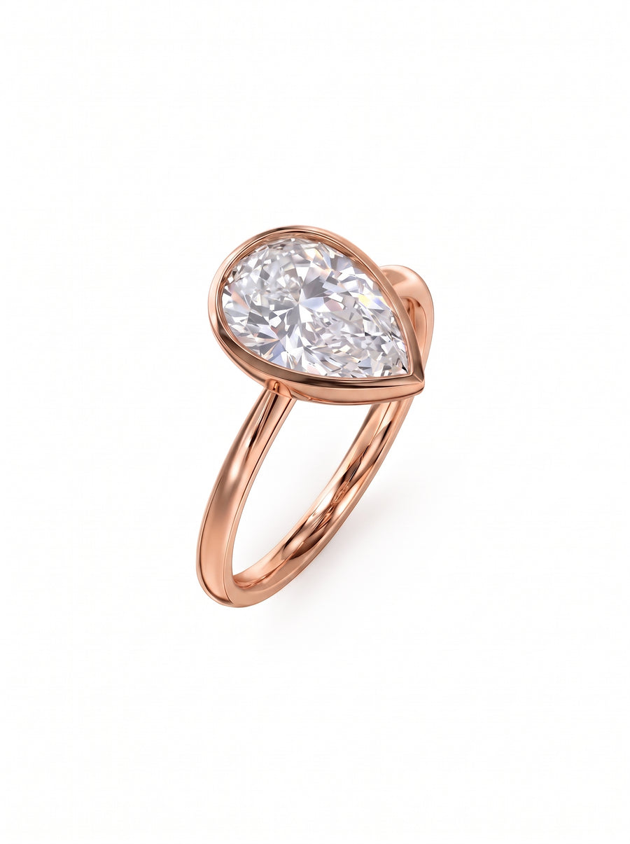 Pear cut diamond engagement ring in a rose gold bezel setting on a white background.