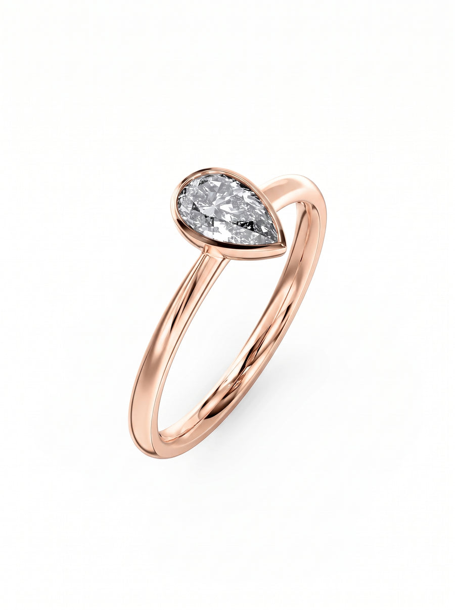 Pear cut diamond engagement ring in a rose gold bezel setting on a plain band.