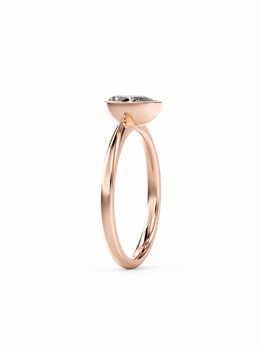 Pear cut diamond engagement ring with a bezel setting in polished rose gold.