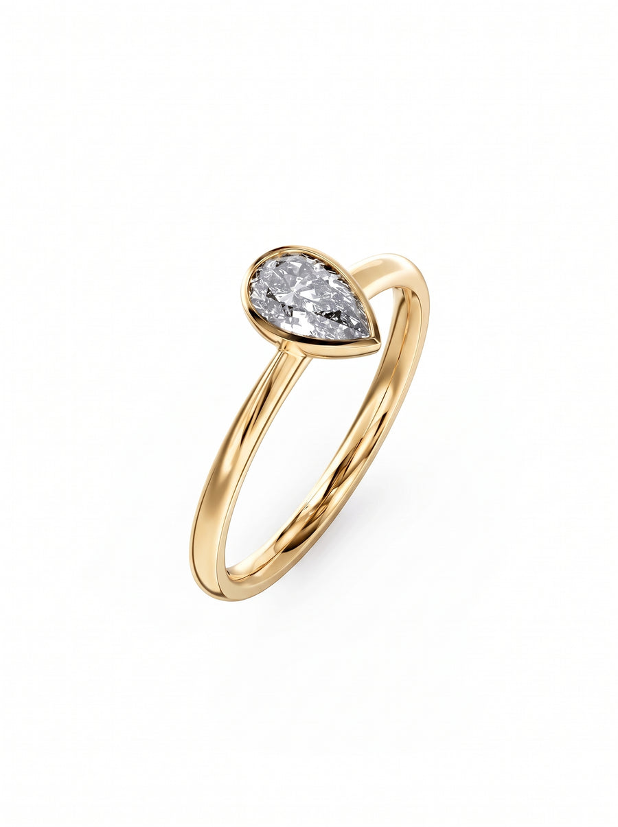 Pear cut diamond engagement ring in a gold bezel setting on a plain gold band.