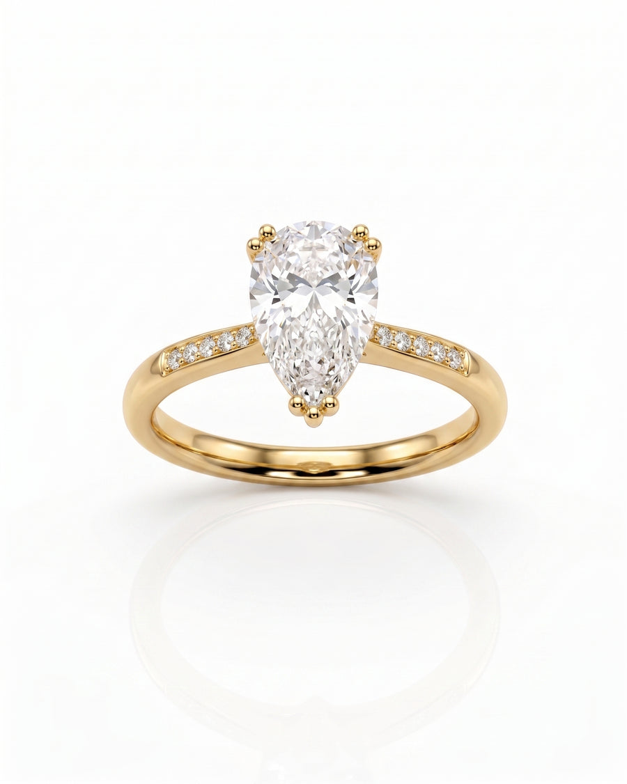Gold engagement ring with a pear cut diamond and pavé band.