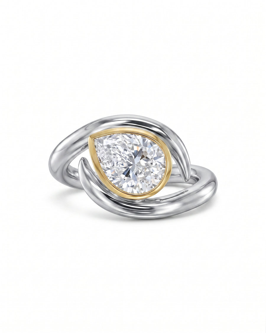 Two-tone ring with a pear-cut diamond in a yellow gold bezel setting.