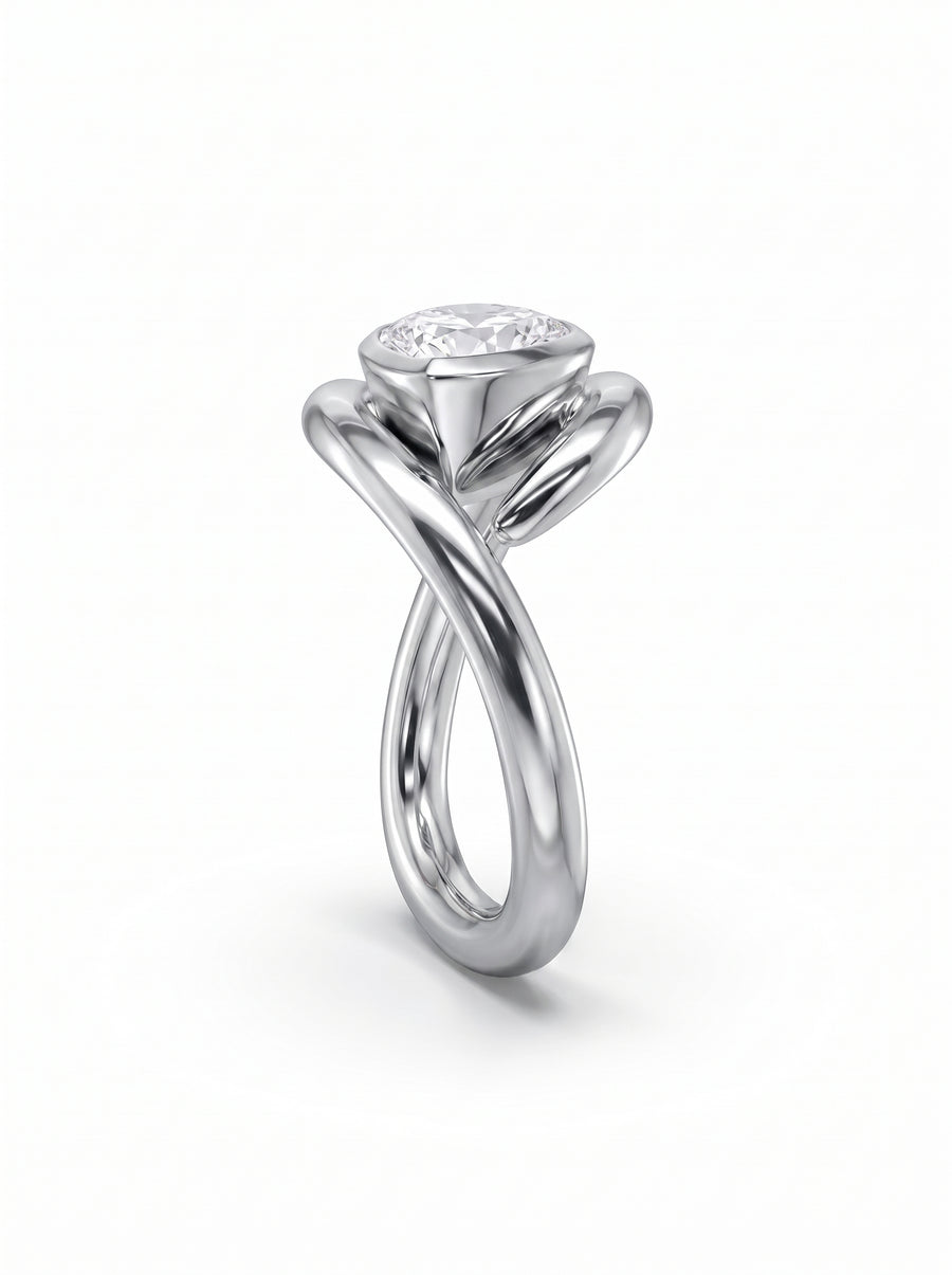 Silver engagement ring with a pear-cut diamond in a bezel setting and a twisted, spiky metal band.