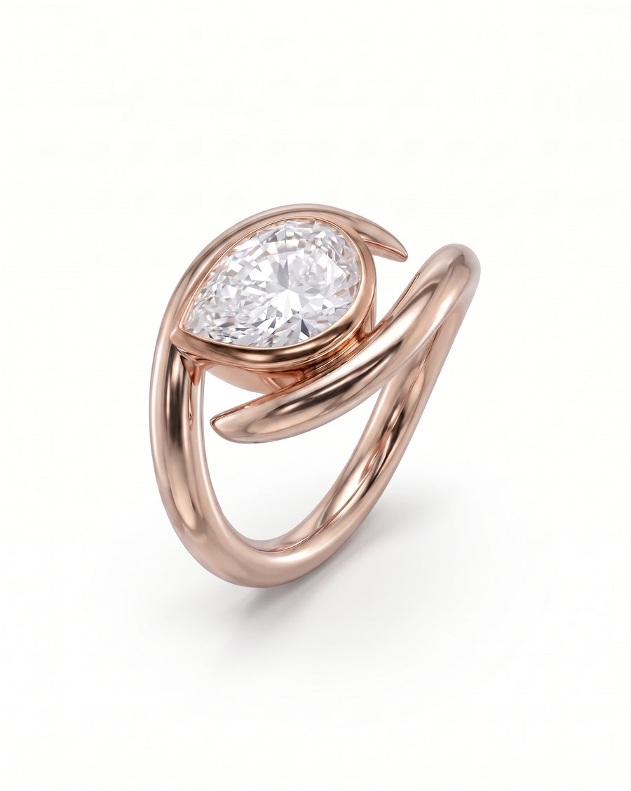 Rose gold engagement ring featuring a pear cut diamond in a unique spiky, wrap-around metal setting.