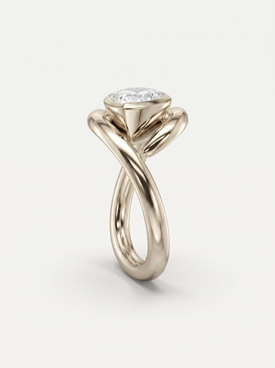 Gold engagement ring with a pear cut diamond in a bezel setting and a twisted, spiky band design.