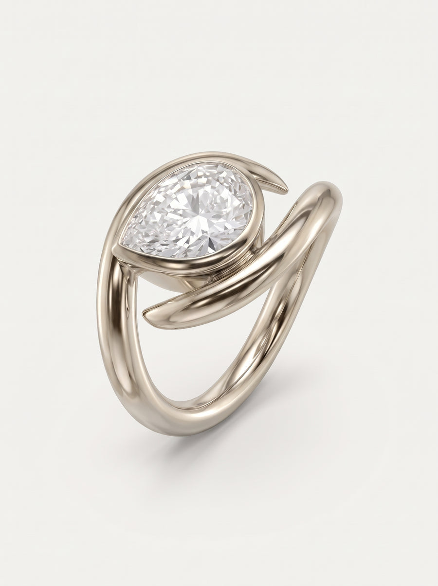 Pear cut diamond engagement ring with a spiky, wrap-around silver band design on a white background.