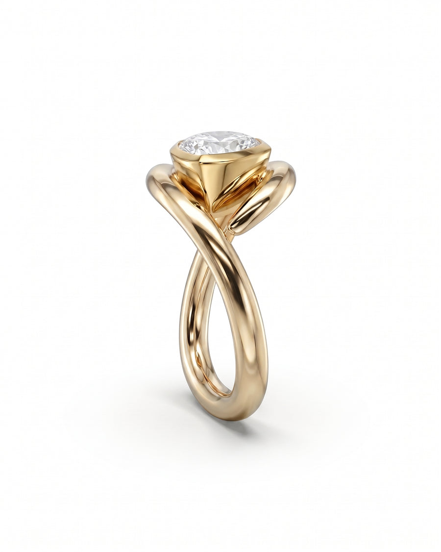 Gold engagement ring featuring a pear cut diamond in a bezel setting with a twisted, spiky band design.