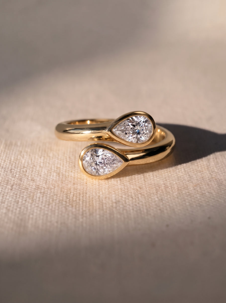 Gold toi et moi engagement ring featuring two pear-cut diamonds in bezel settings on a polished band.