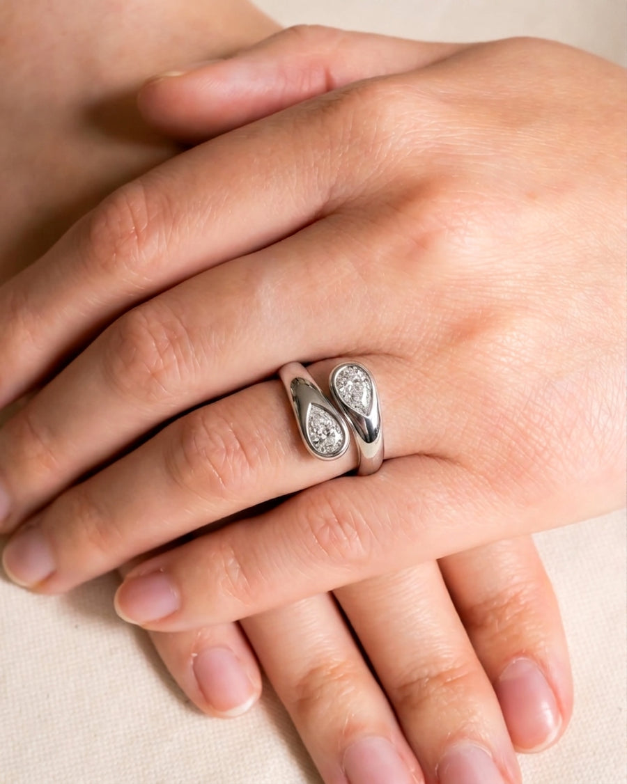 Silver toi et moi ring with two pear-cut diamond clusters on a hand.