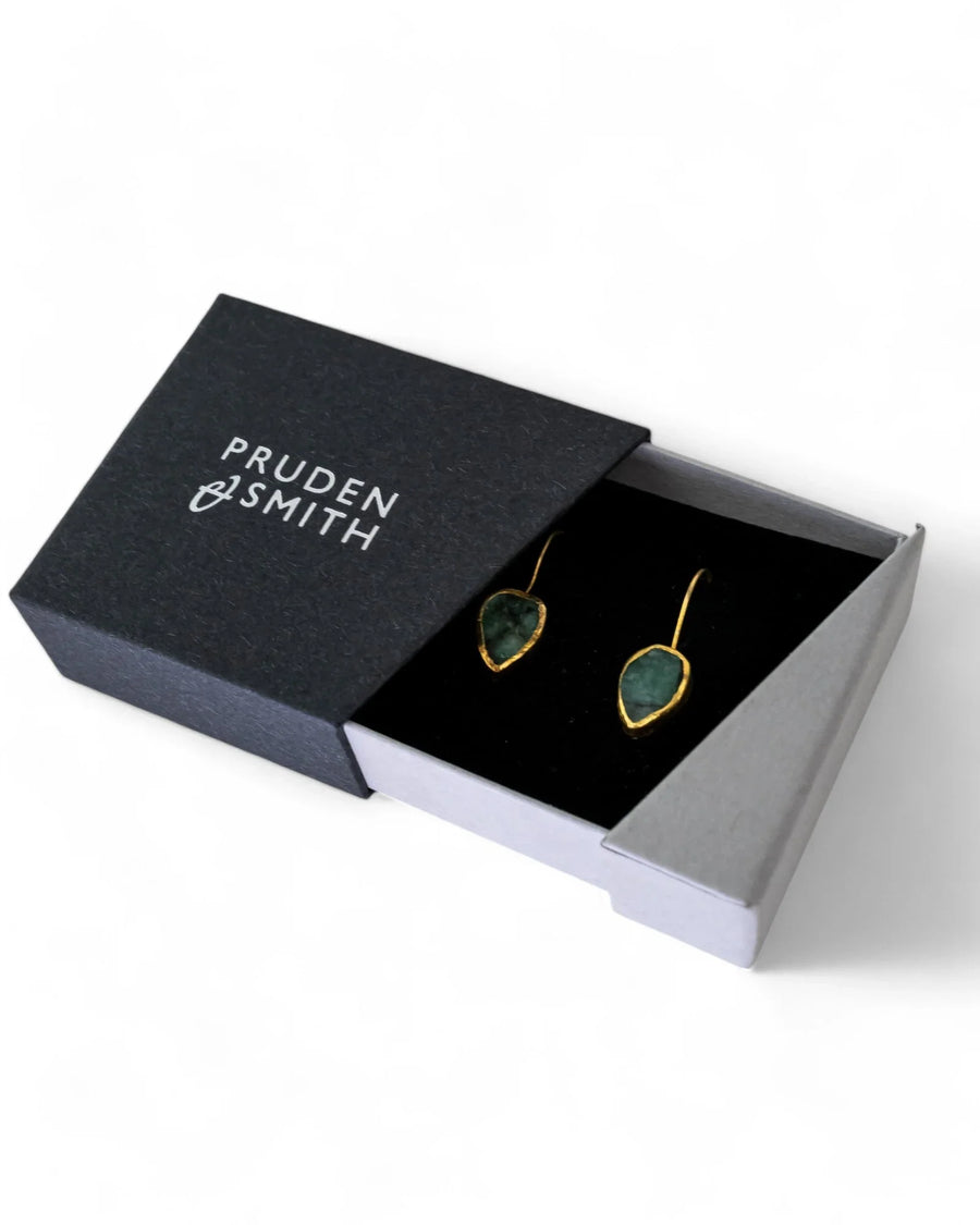 Pear-shaped rough emerald drop earrings with gold edges in a gift box