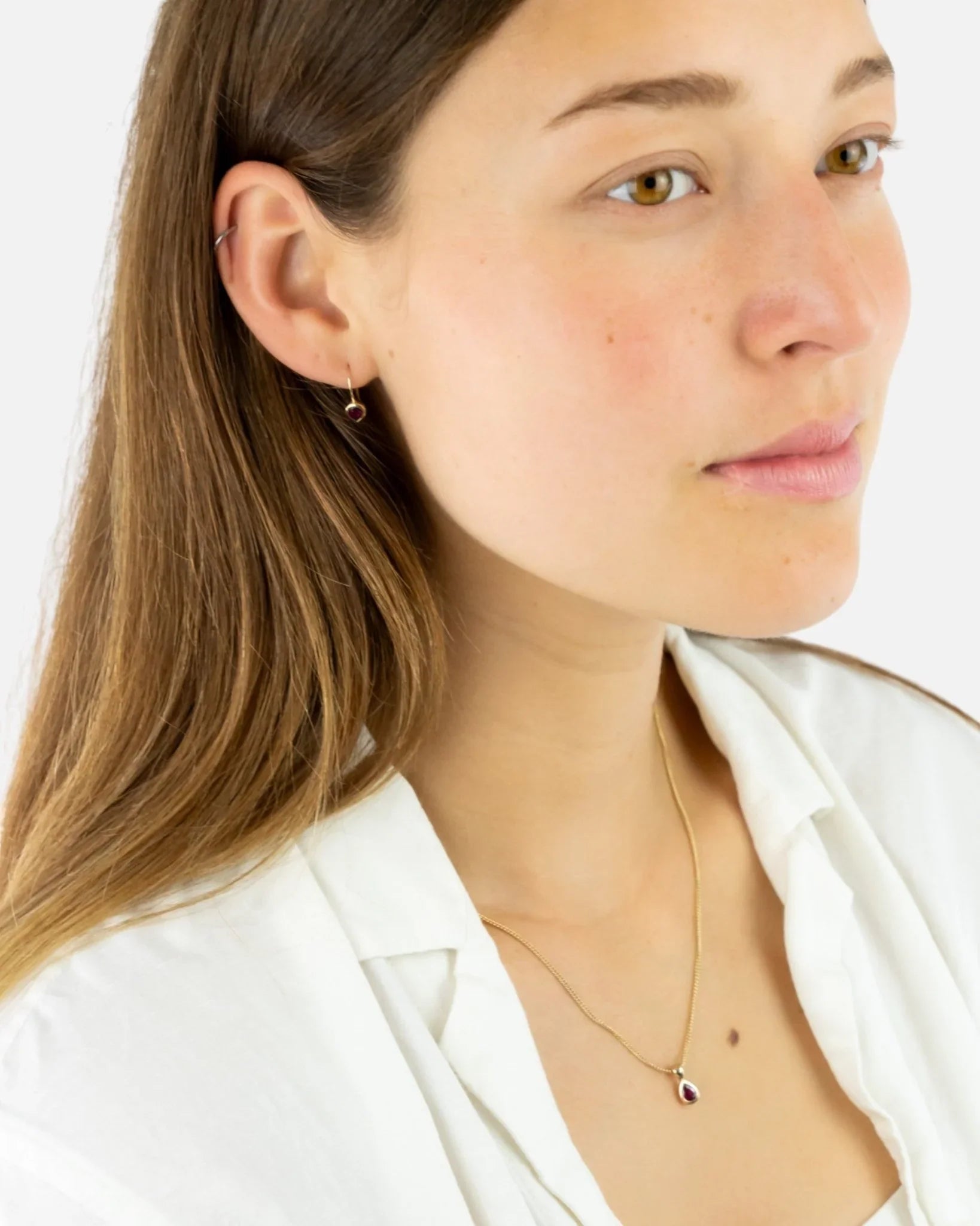Woman wearing a pear-shaped ruby pendant on a 9ct yellow gold chain necklace