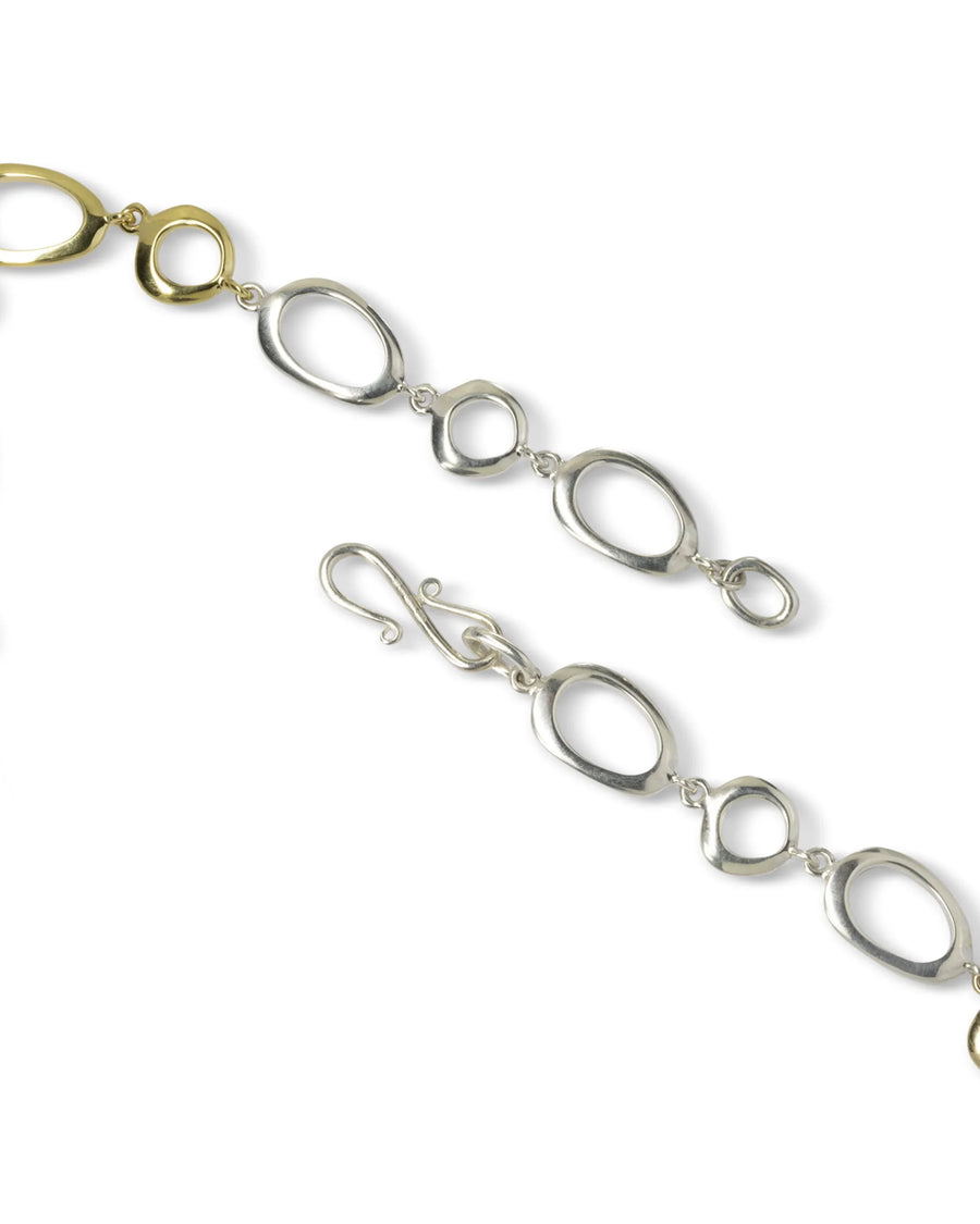 Organic pebble-link necklace in gold and silver with an artisan clasp on white background