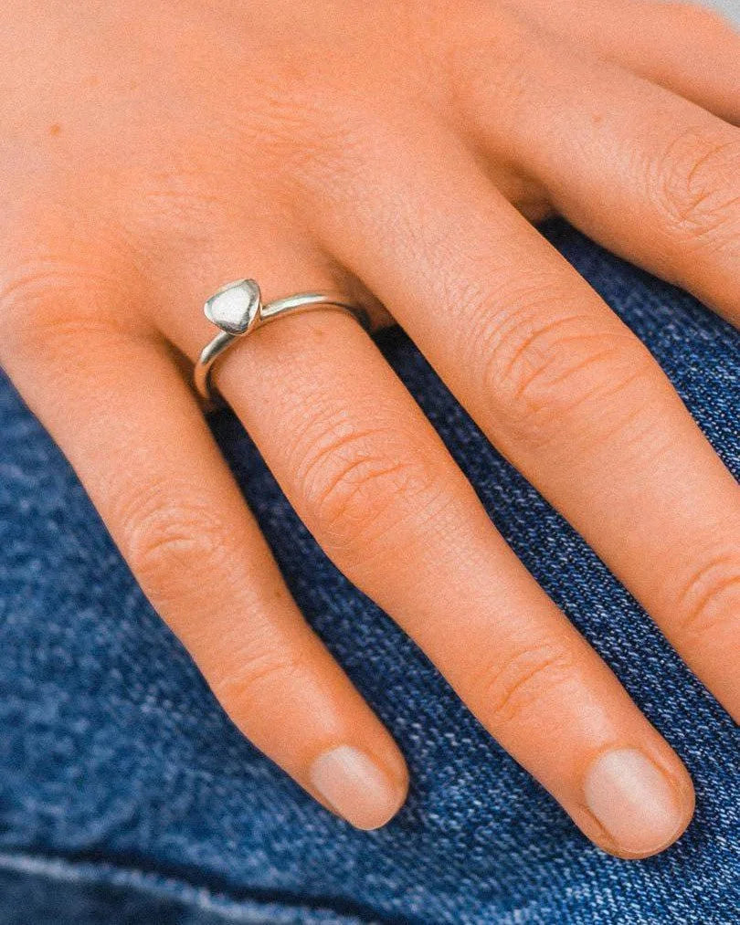Hand wearing a matte gold pebble stacking ring set with organic, modern design