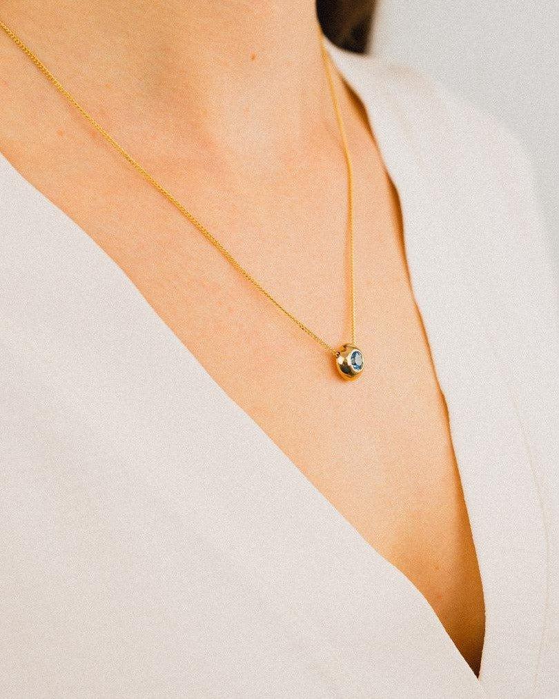 Woman wearing a 9ct yellow gold pendant necklace with an aquamarine gemstone