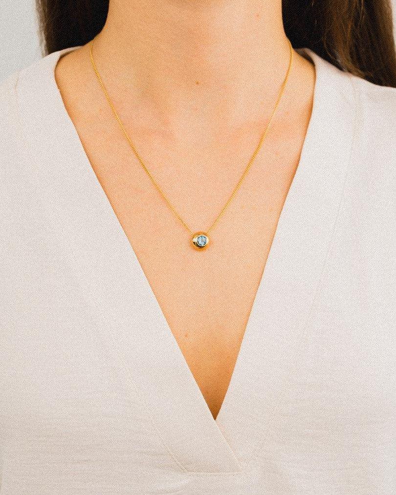 Woman wearing a 9ct yellow gold pendant necklace with aquamarine gemstone