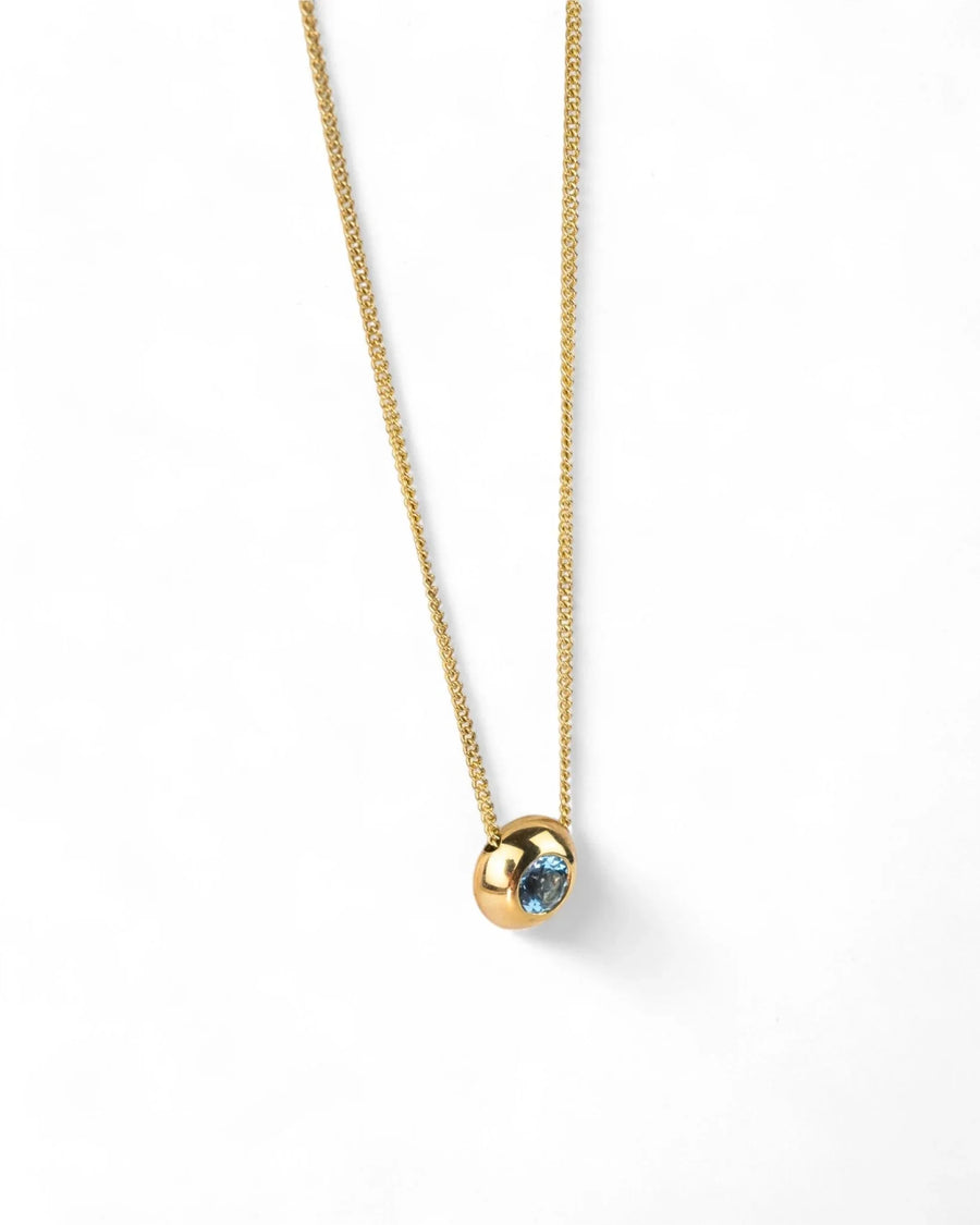 Yellow gold necklace with round aquamarine pendant on a plain white background