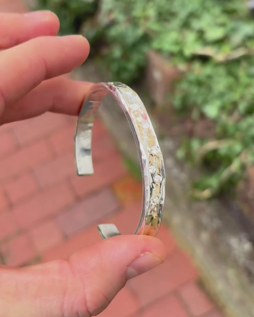 silver and gold diamond set bangle being rotated by hand