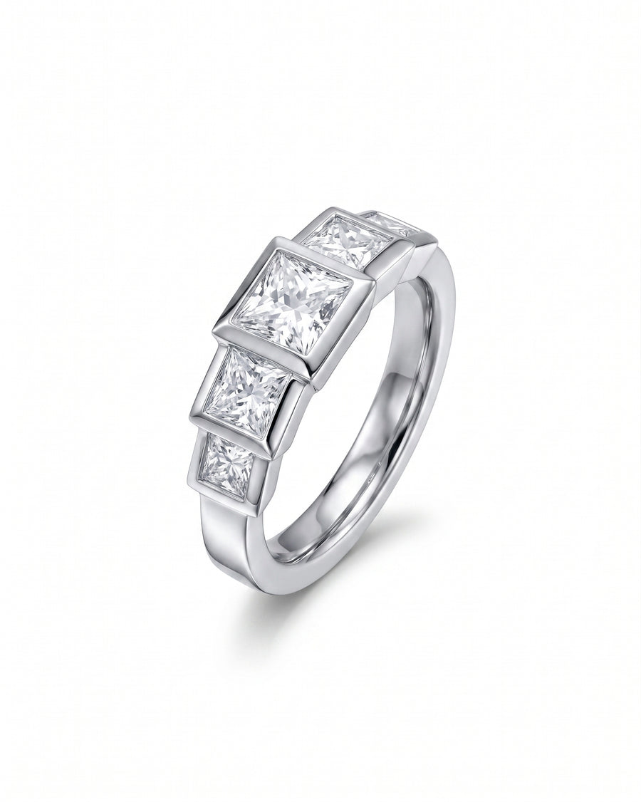Silver ring with three princess cut diamonds in a bezel setting.