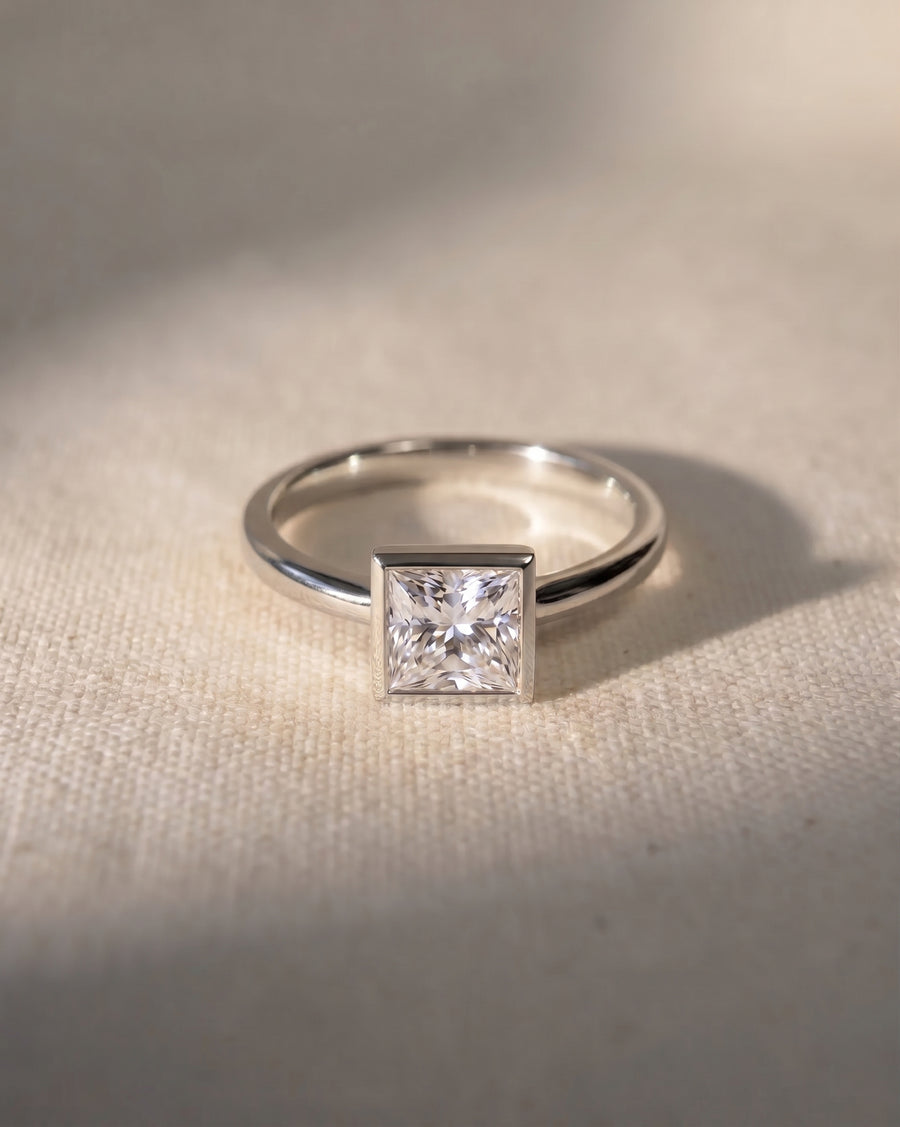 Platinum engagement ring with a princess cut lab-grown diamond in a bezel setting.